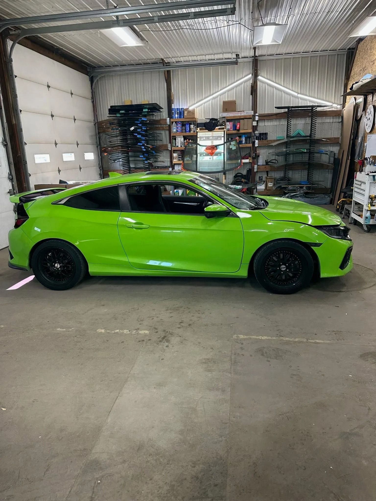 Green car with black wheels in a garage.