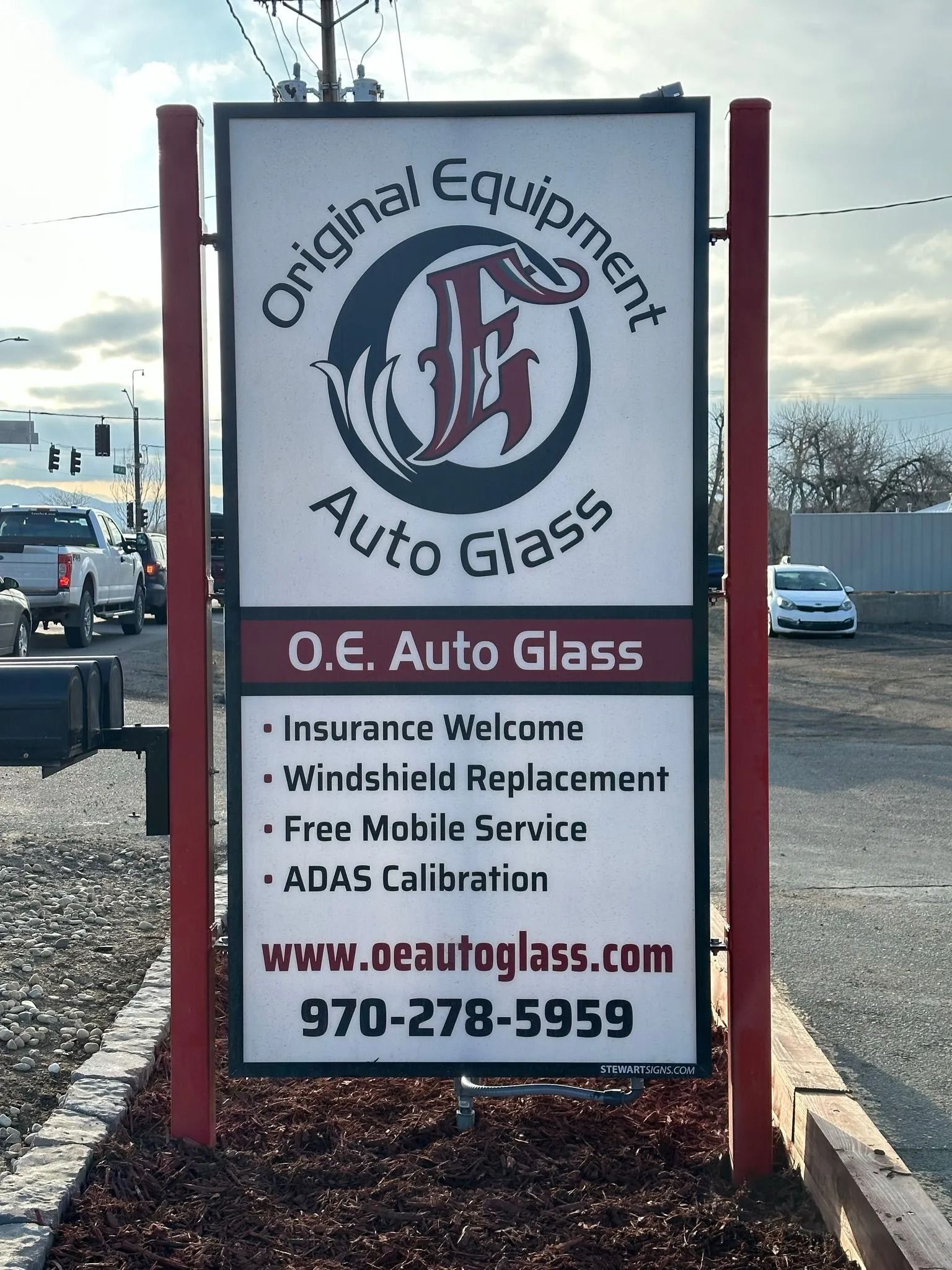 Sign for O.E. Auto Glass with logo, services listed, website, and phone number.