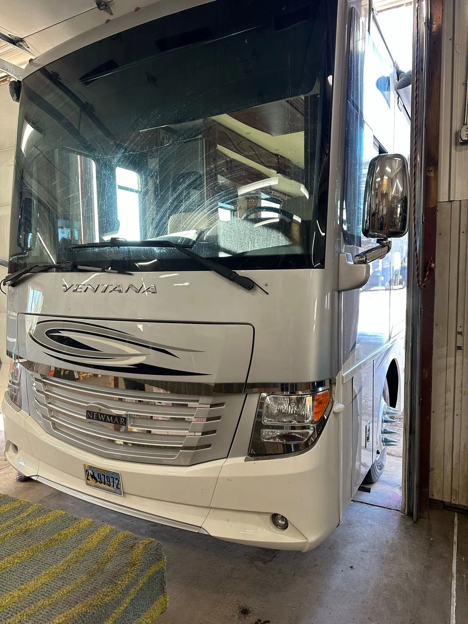 White RV inside a structure, possibly a wash bay, with the front facing the viewer.
