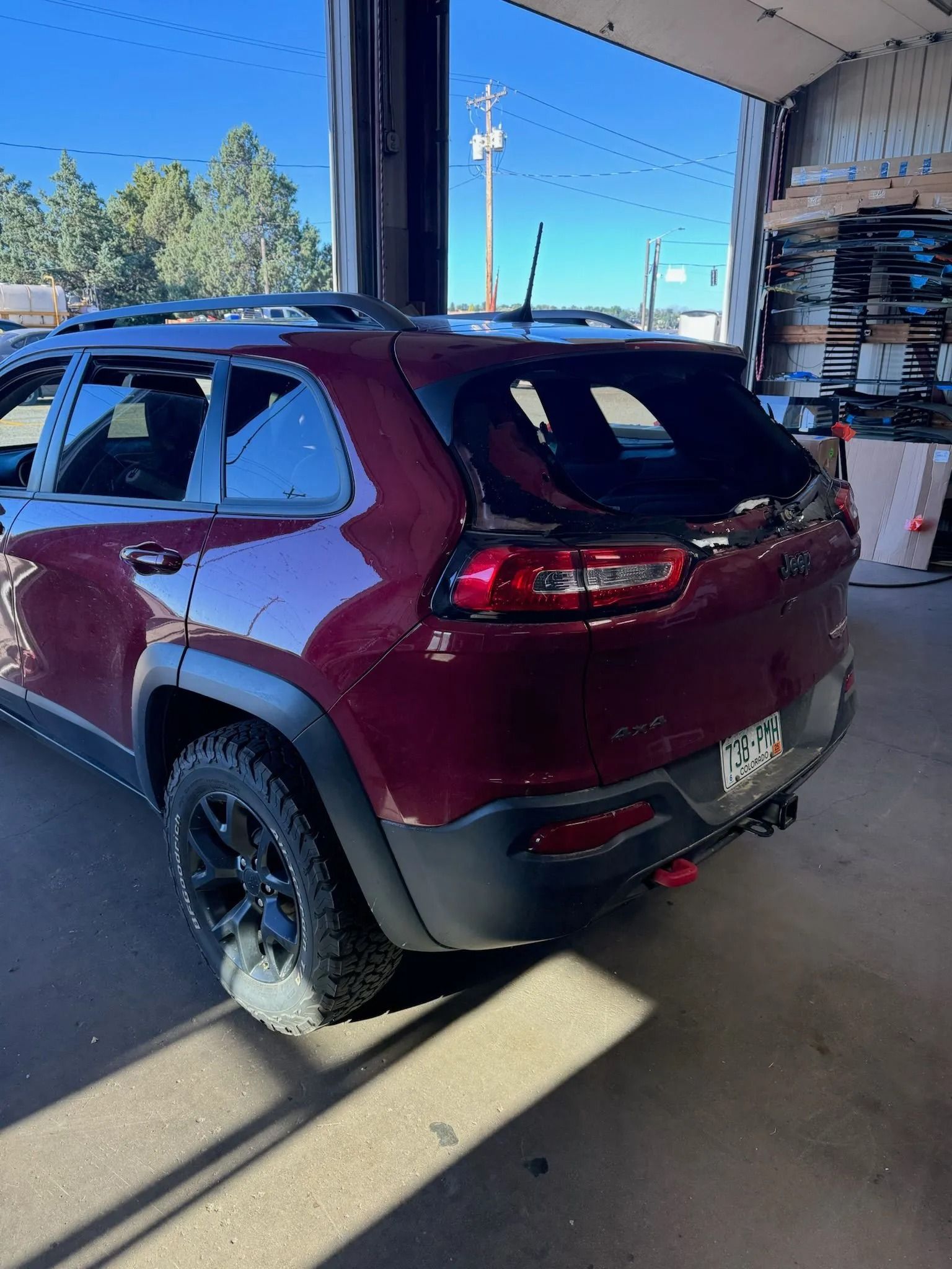 Red Jeep Cherokee SUV parked inside a garage, next to tires.