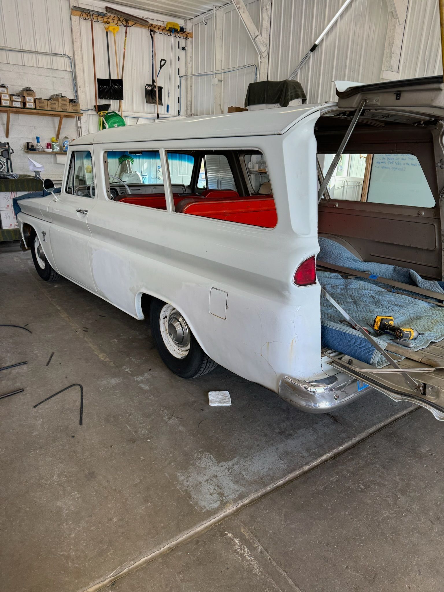 White vintage station wagon being restored in a workshop, with open rear.