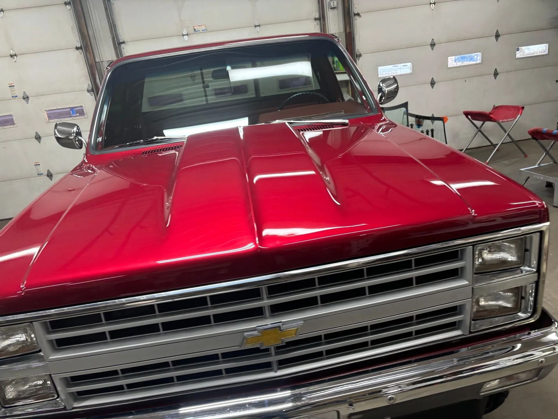 Red Chevrolet pickup truck with a shiny, reflective hood, parked indoors.