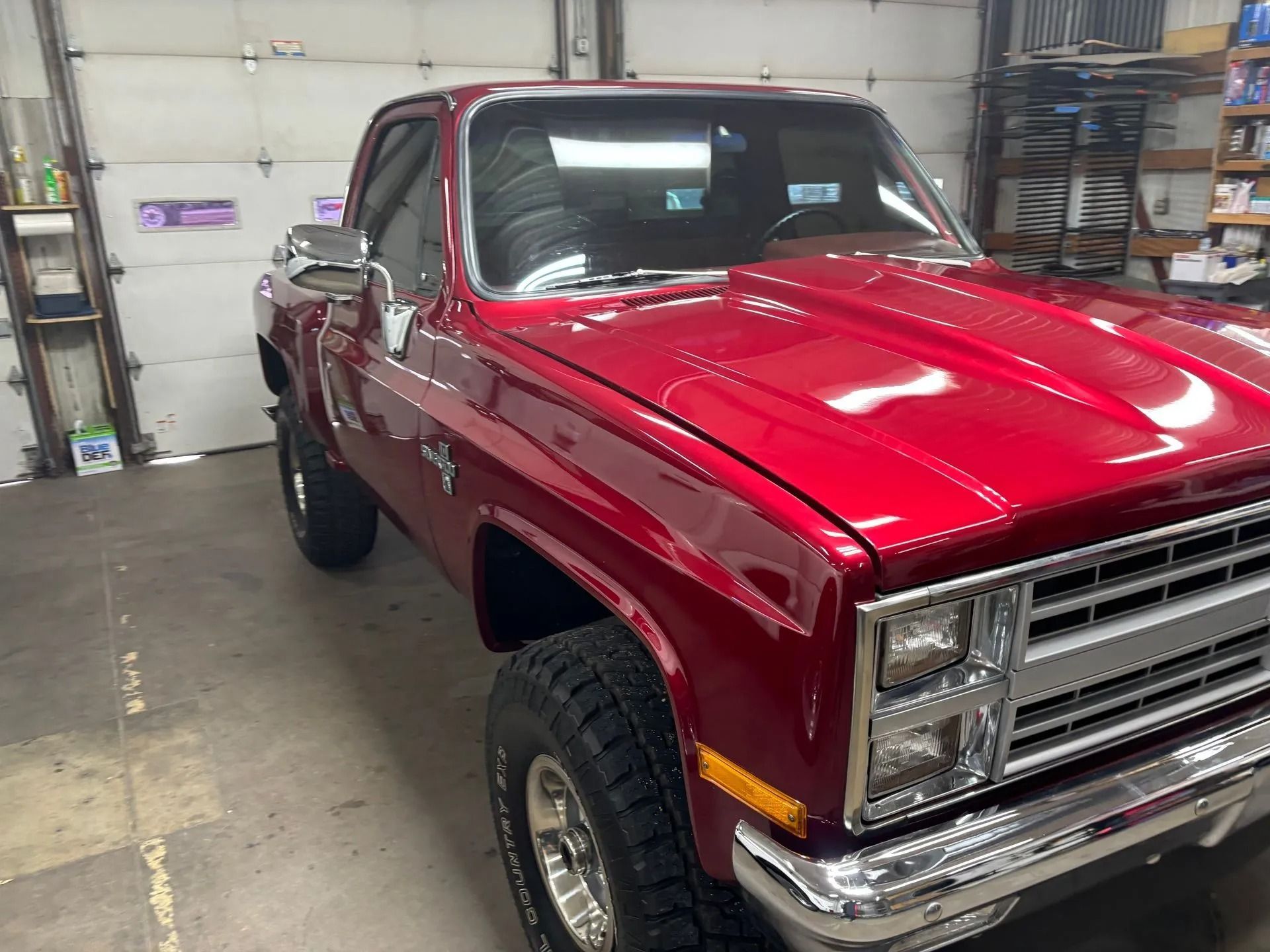 Red classic Chevrolet pickup truck parked in a garage with chrome details.