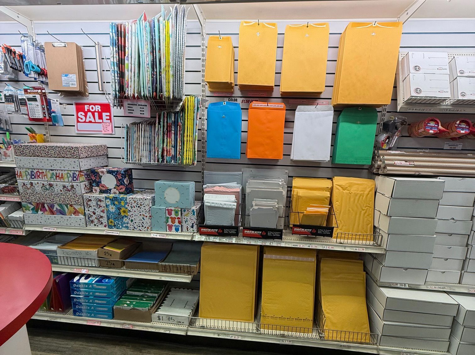Shelves in a store filled with stationery supplies, including envelopes in various colors and sizes.