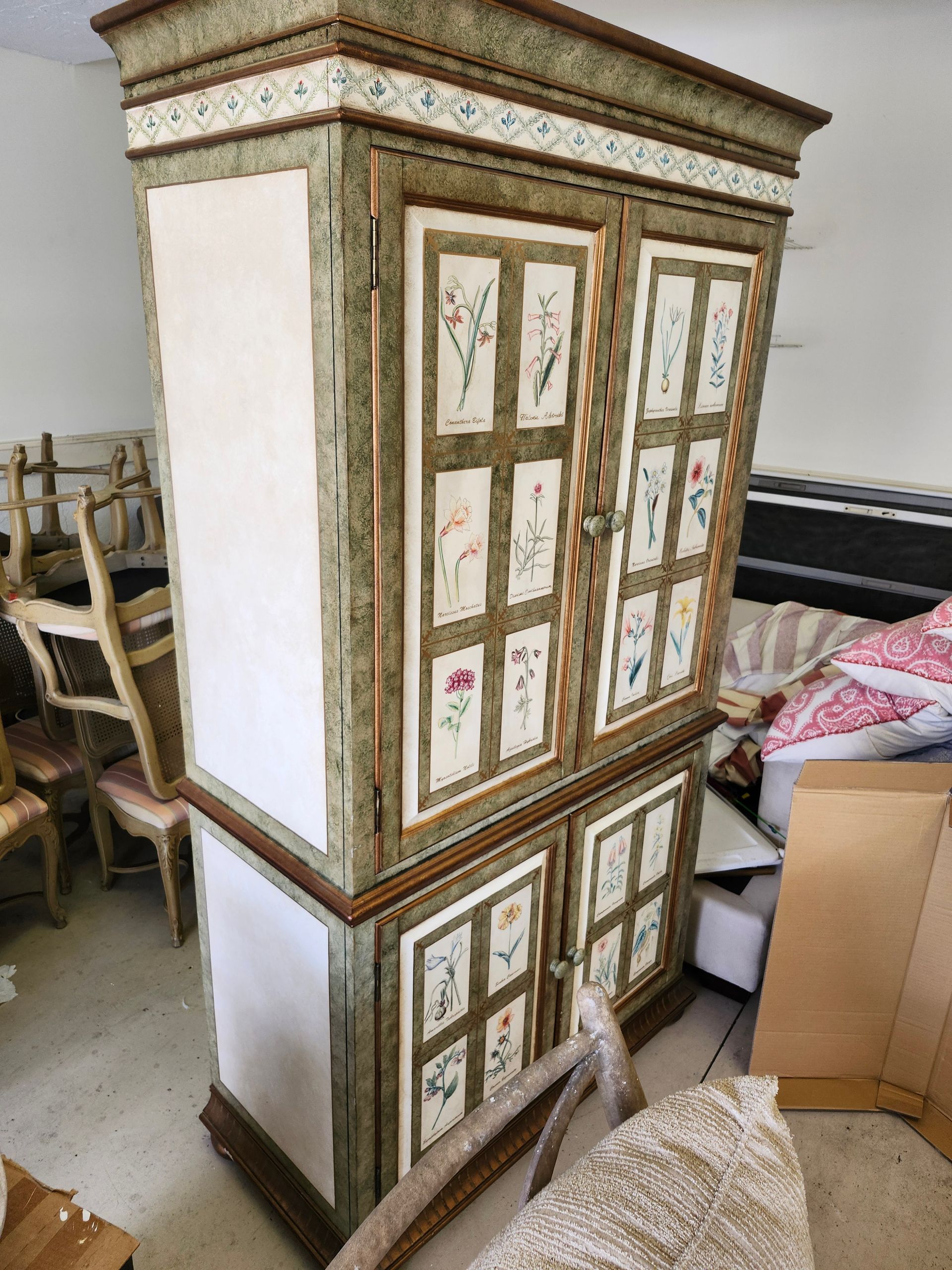Tall, ornate cabinet with floral accents in a room with other furniture.