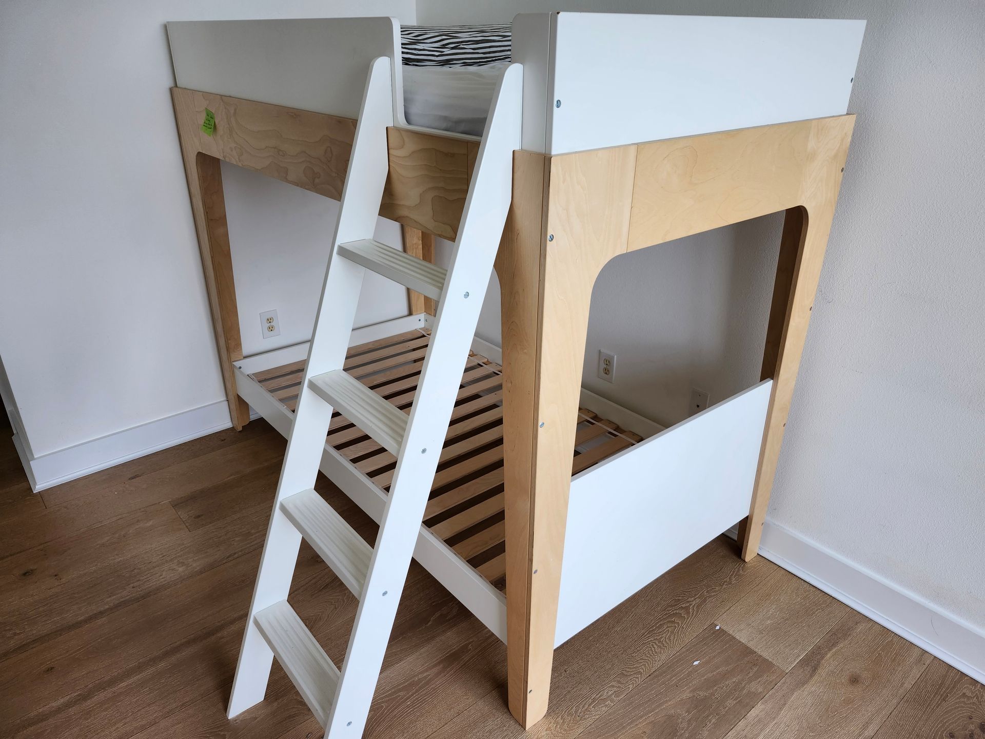 Bunk bed with white frame, wooden ladder, and light-colored wood accents.