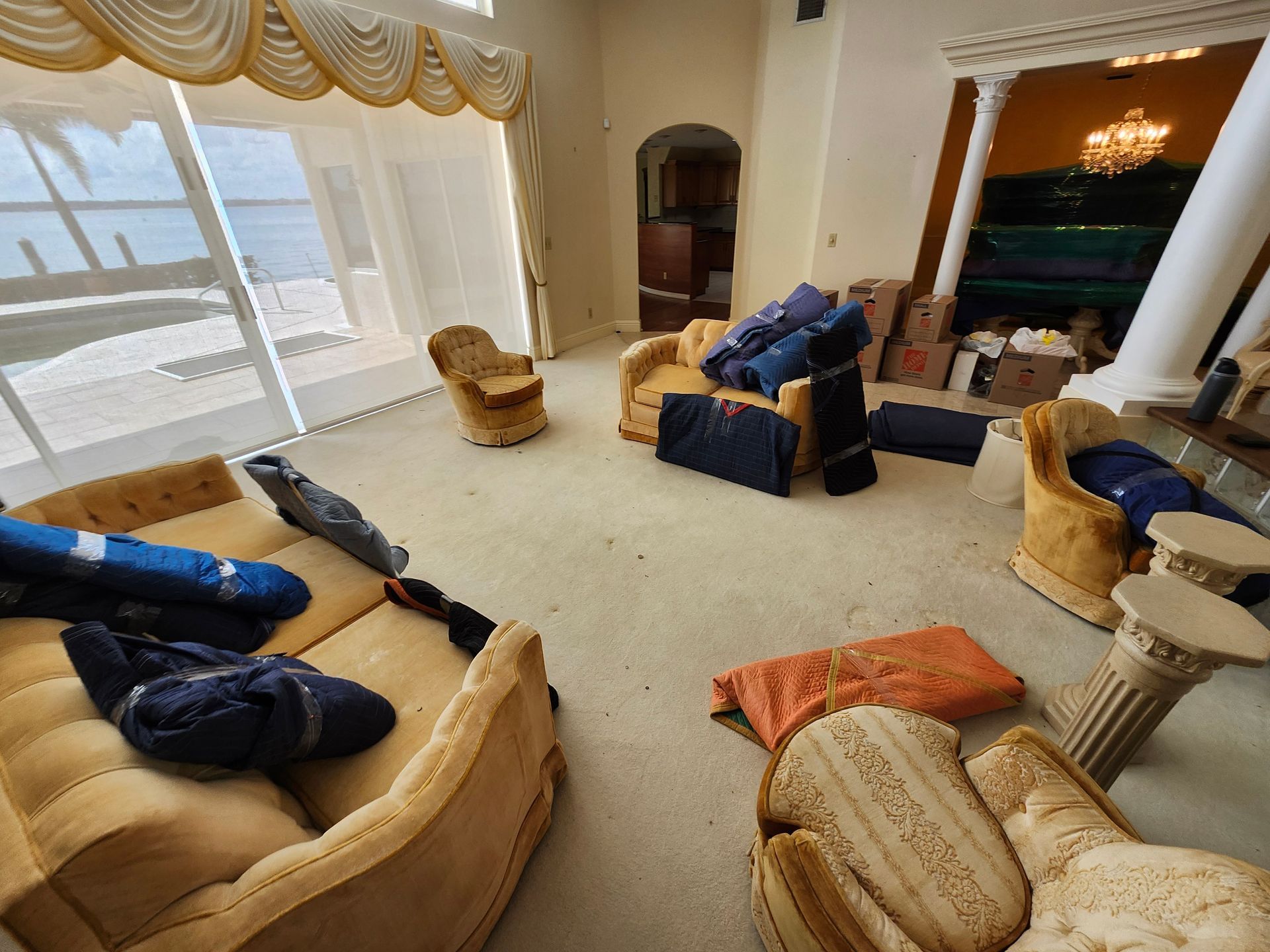 Living room with furniture; beige, blue, and orange cushions scattered on a light carpet.