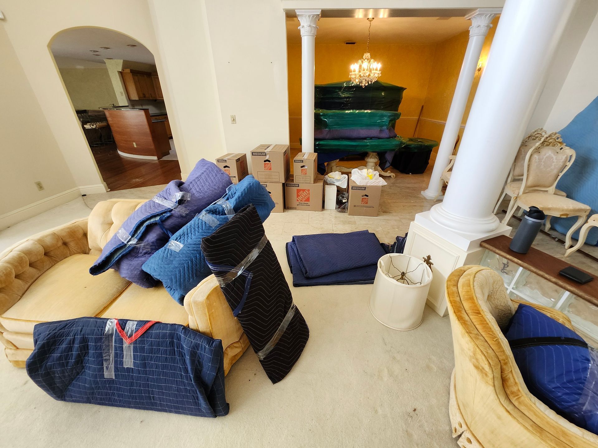 Moving day: furniture pads, boxes, and a piano inside a home.