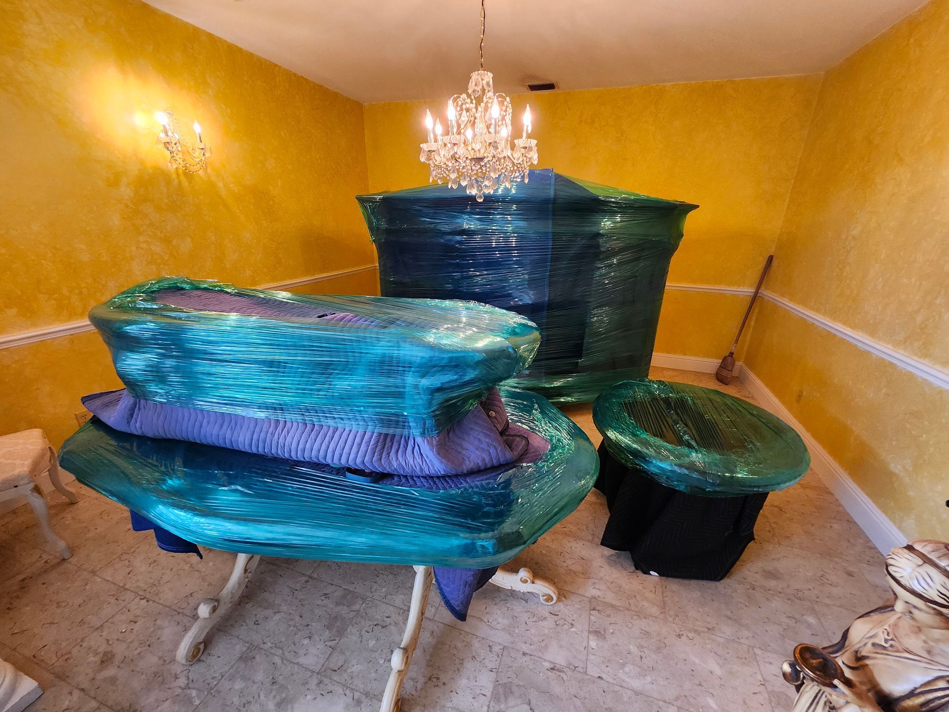 A room with turquoise, abstract sculptures and a chandelier against yellow walls.