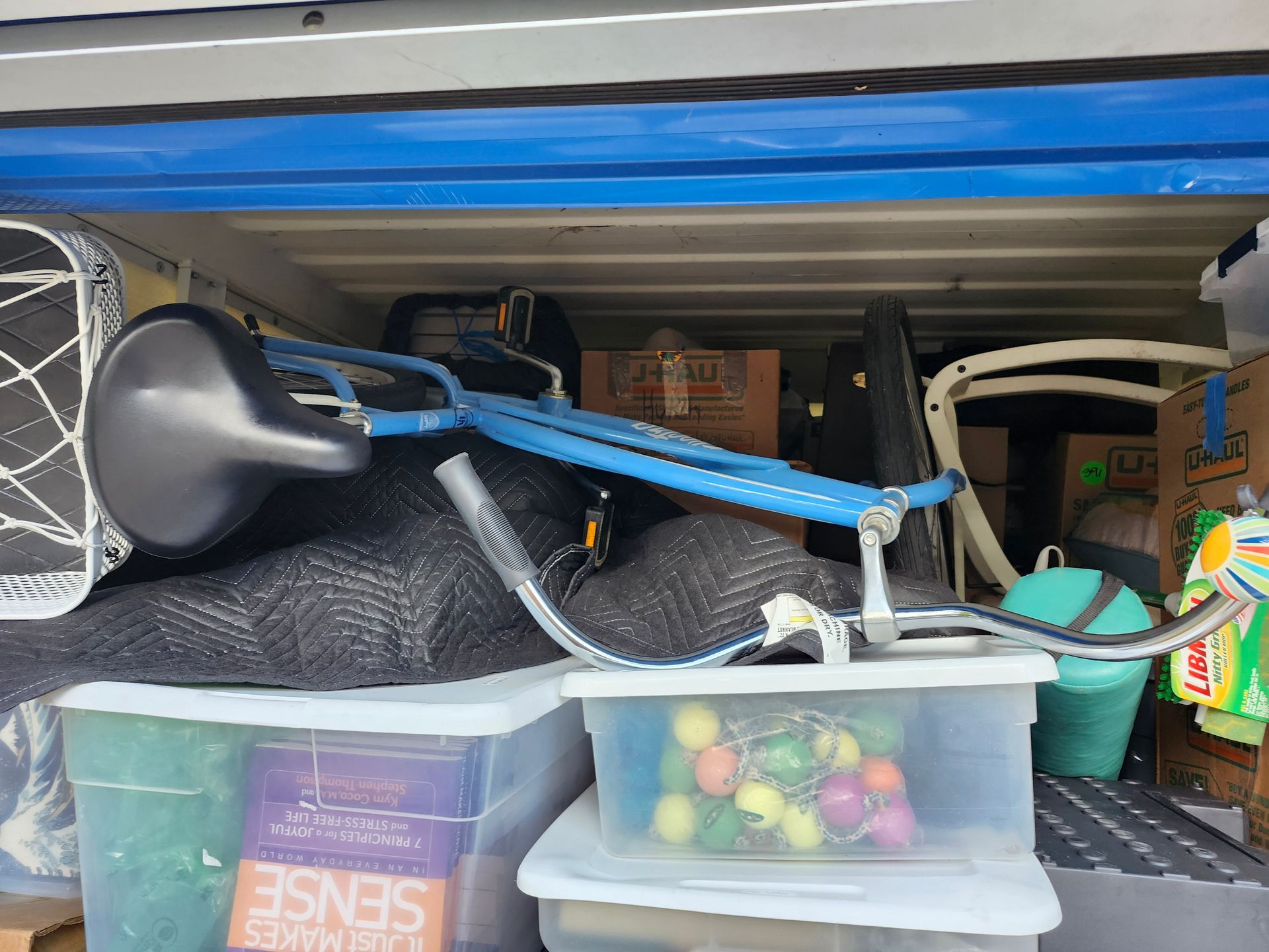 Open storage unit, blue bicycle, clear storage bins, packed items, and blue trim.