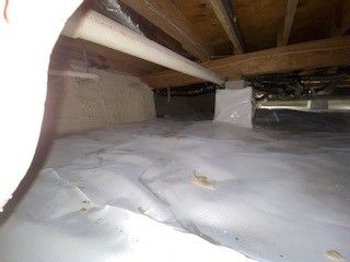 A person is standing in the crawl space of a house.