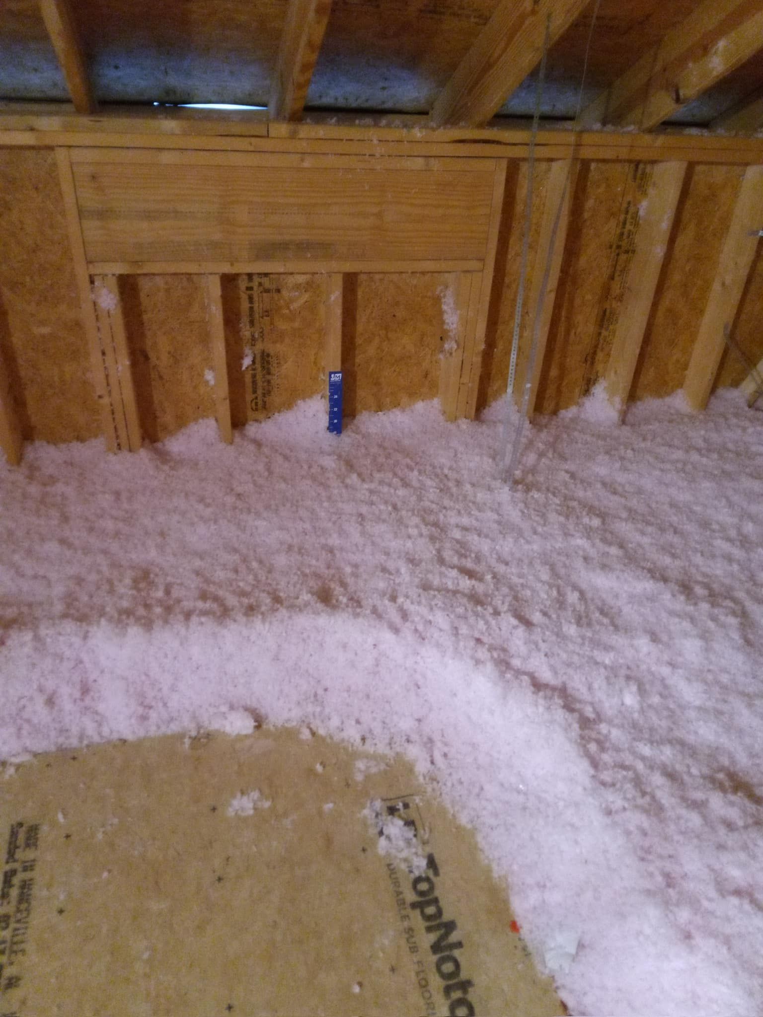 There is a blue pipe in the attic of a house.