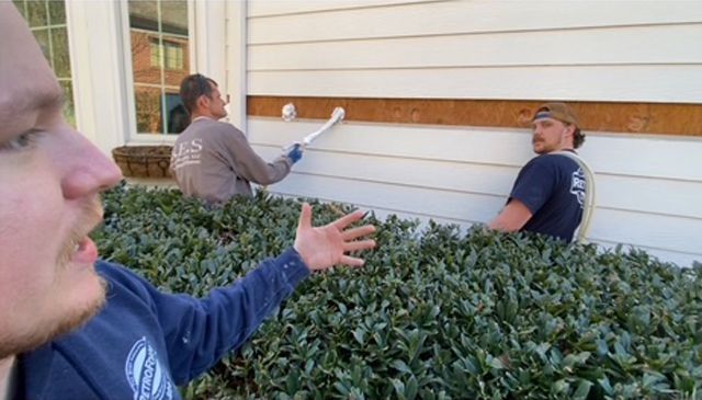 A group of men are painting the side of a house