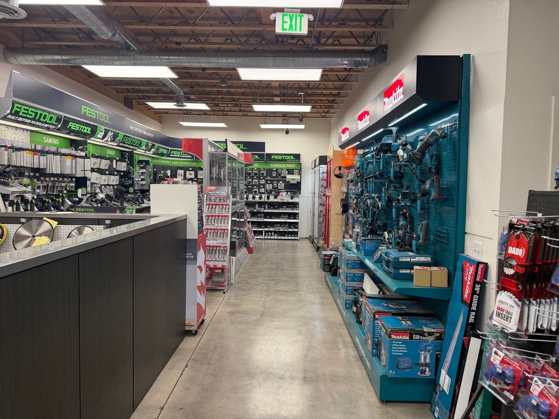 Aisle in a hardware store displaying power tools and accessories, with an exit sign overhead.