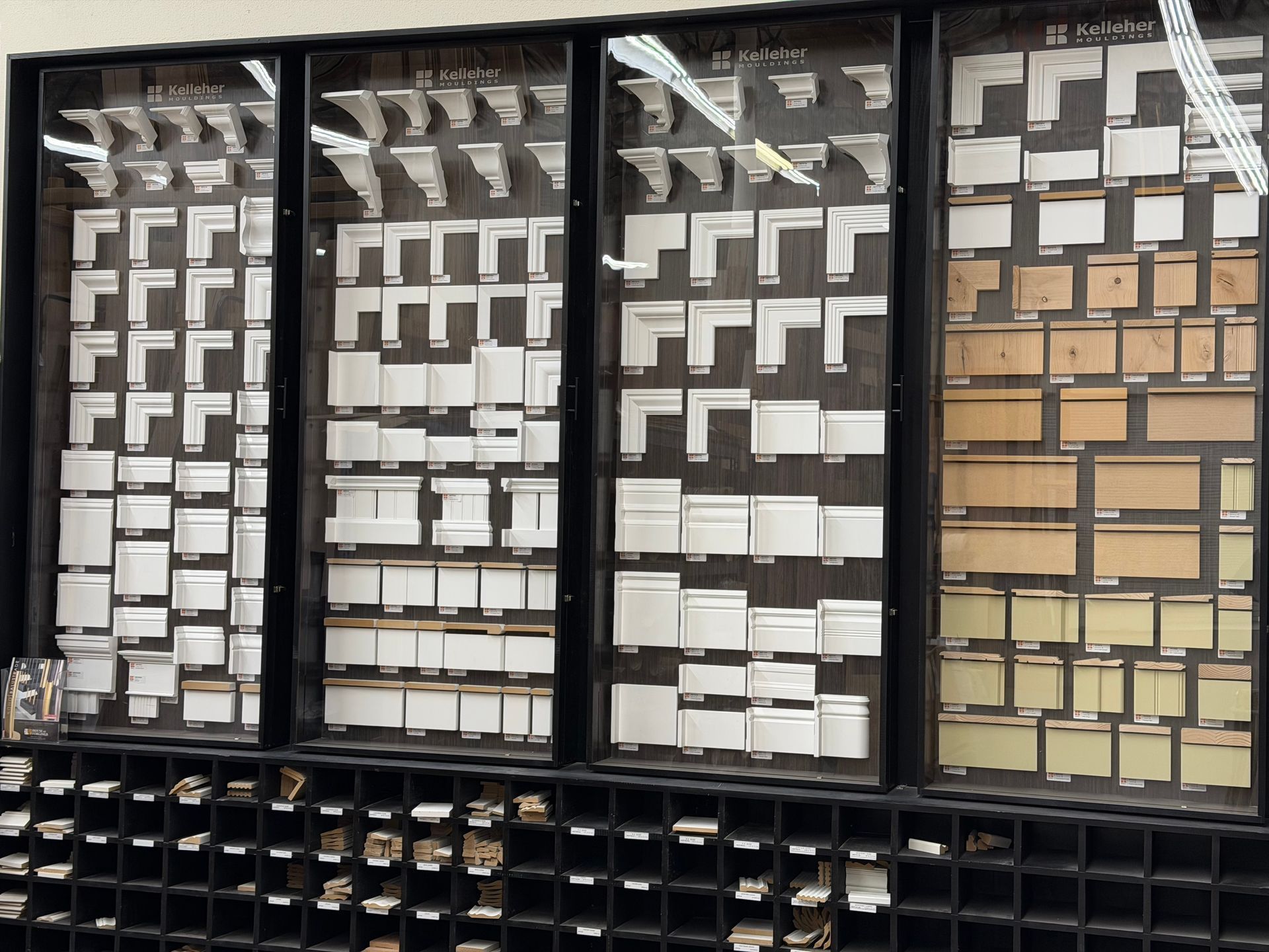 Display of molding samples in a store, showcasing various shapes and sizes in white and wood tones.