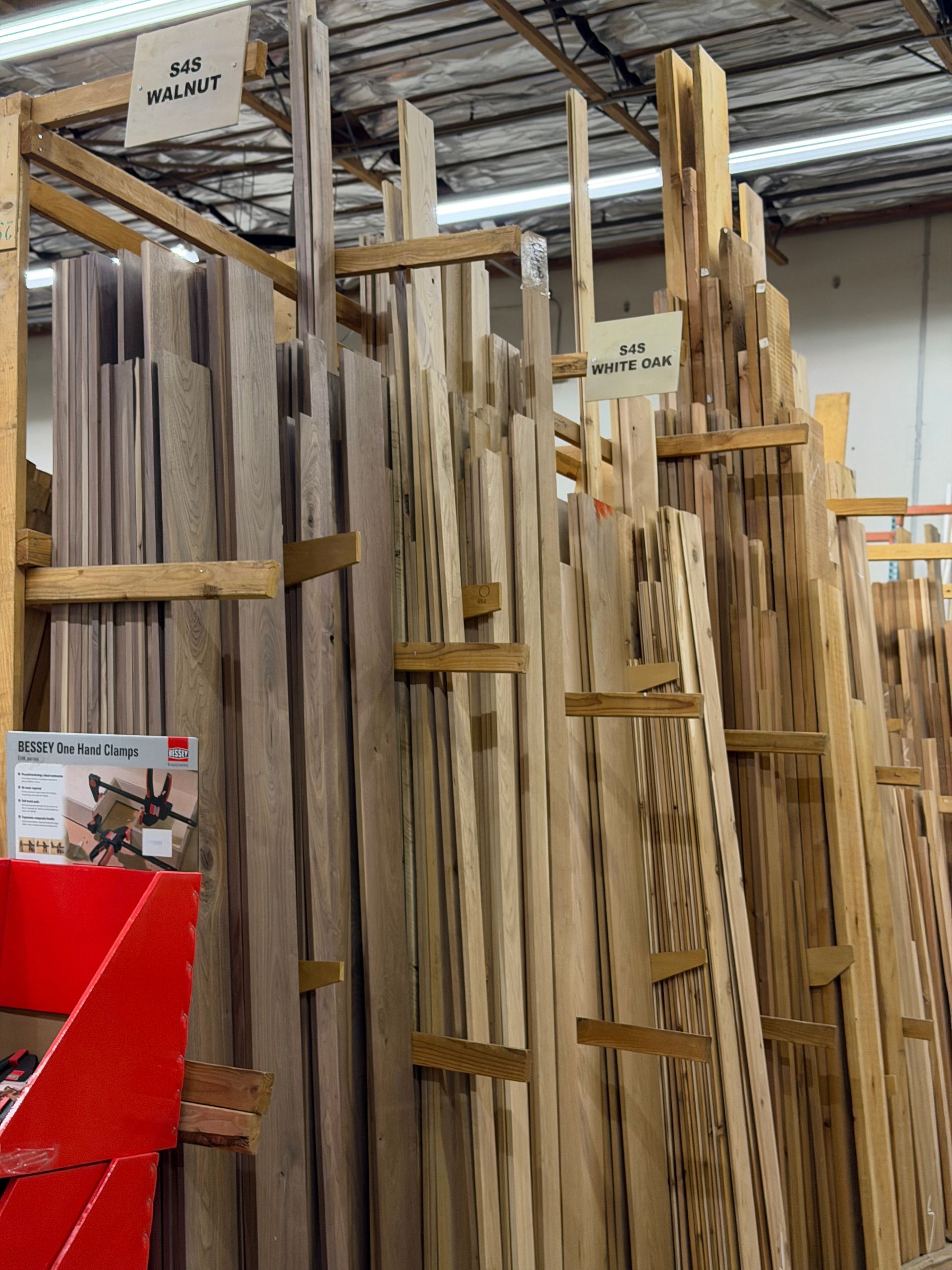 Wood planks stored vertically in a lumberyard, labeled with product information.