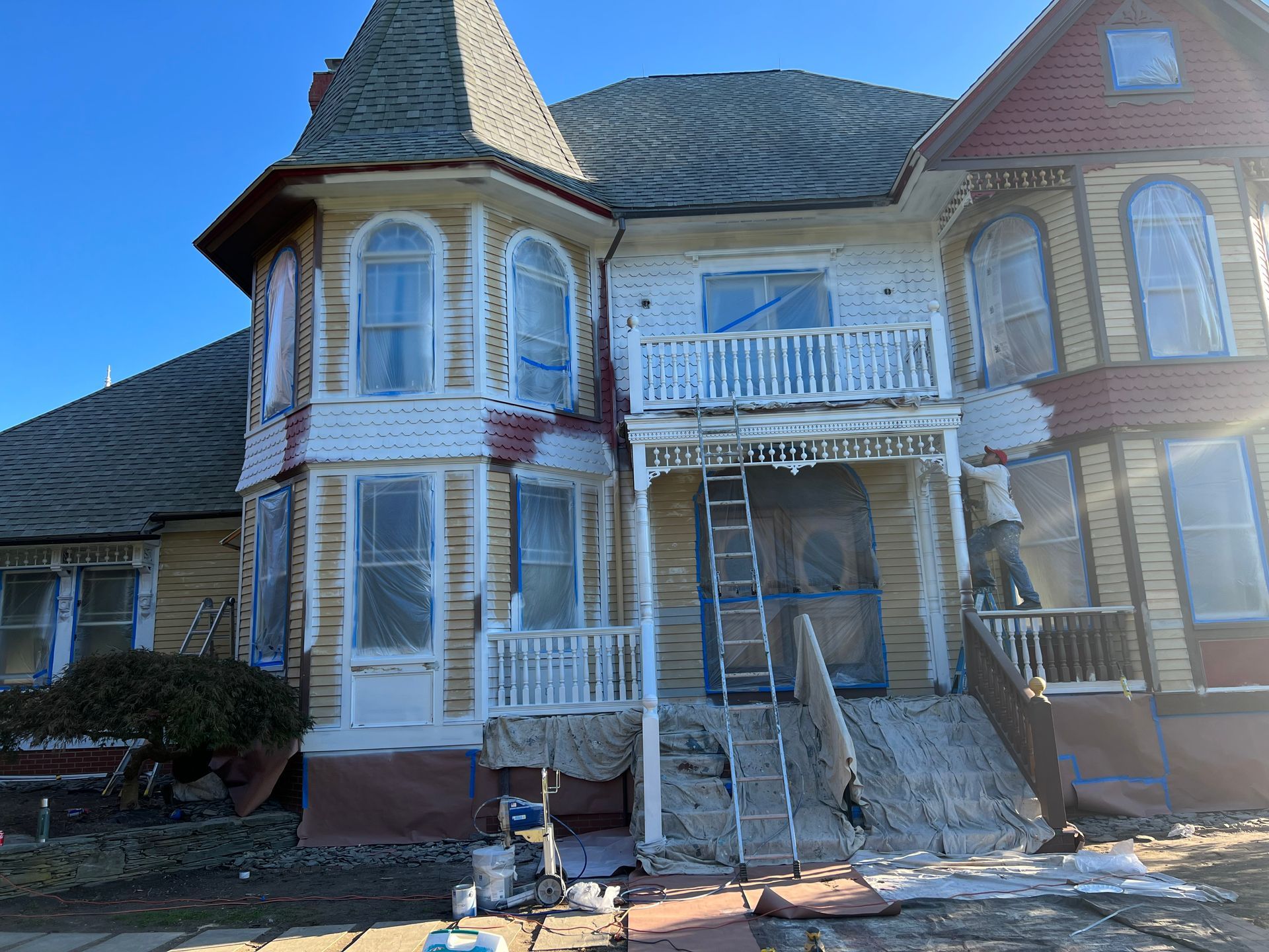 A large house is being painted by a group of people.