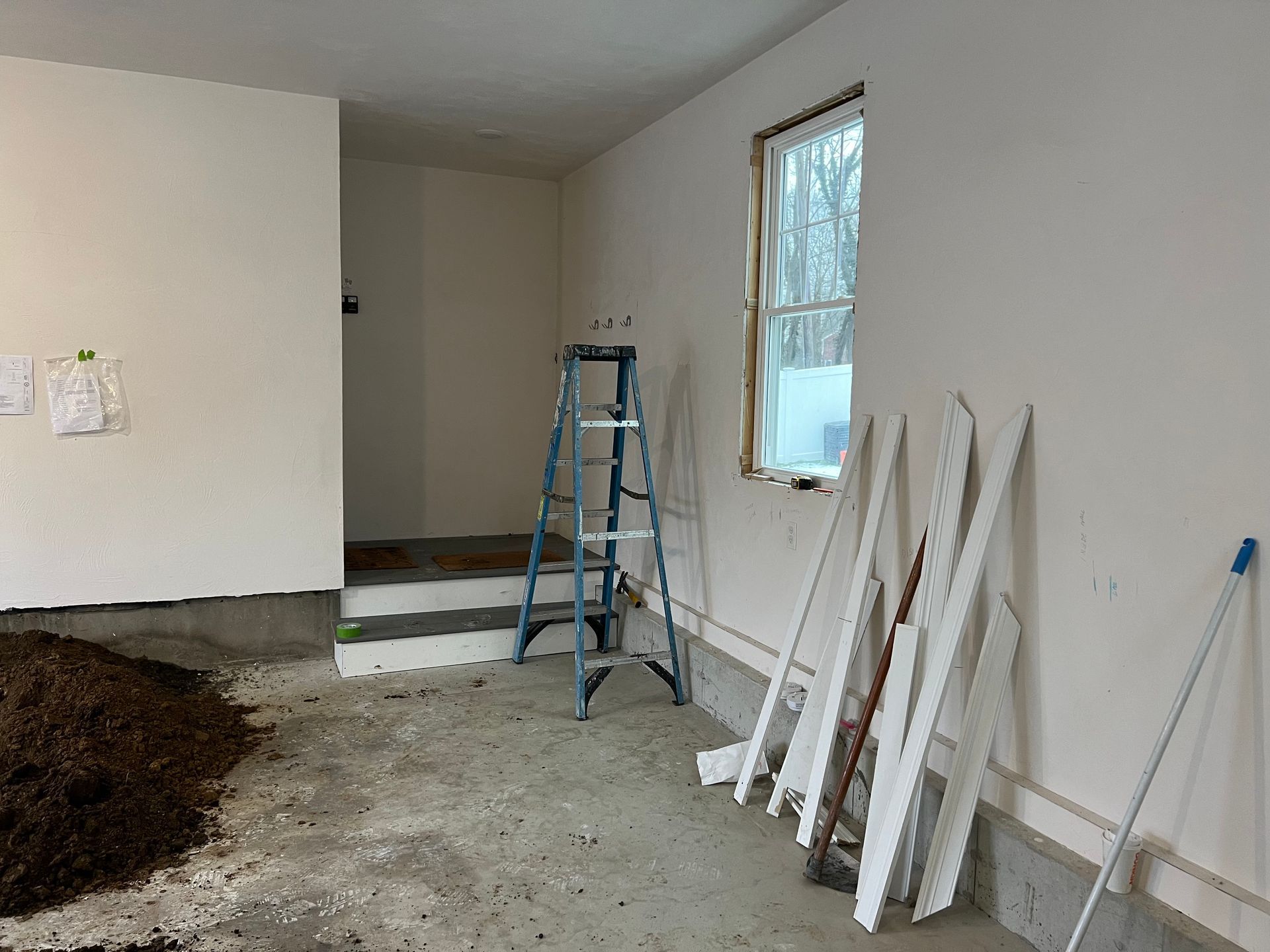 A ladder is sitting in a room next to a window.