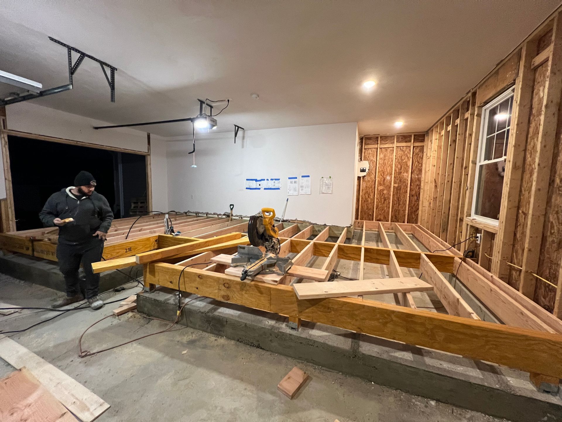 A man is working on a wooden floor in a room under construction.