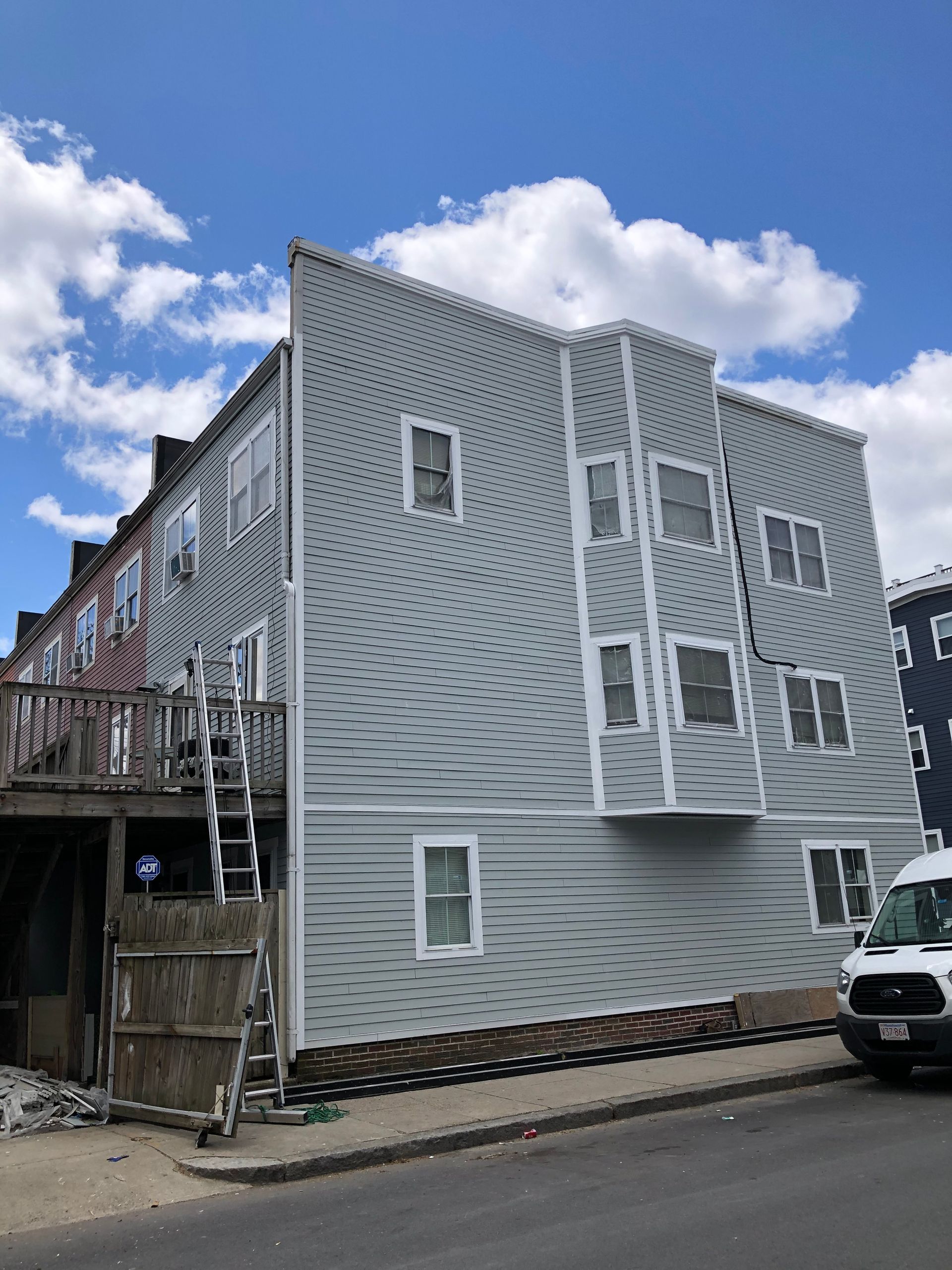 A white van is parked in front of a building under construction.