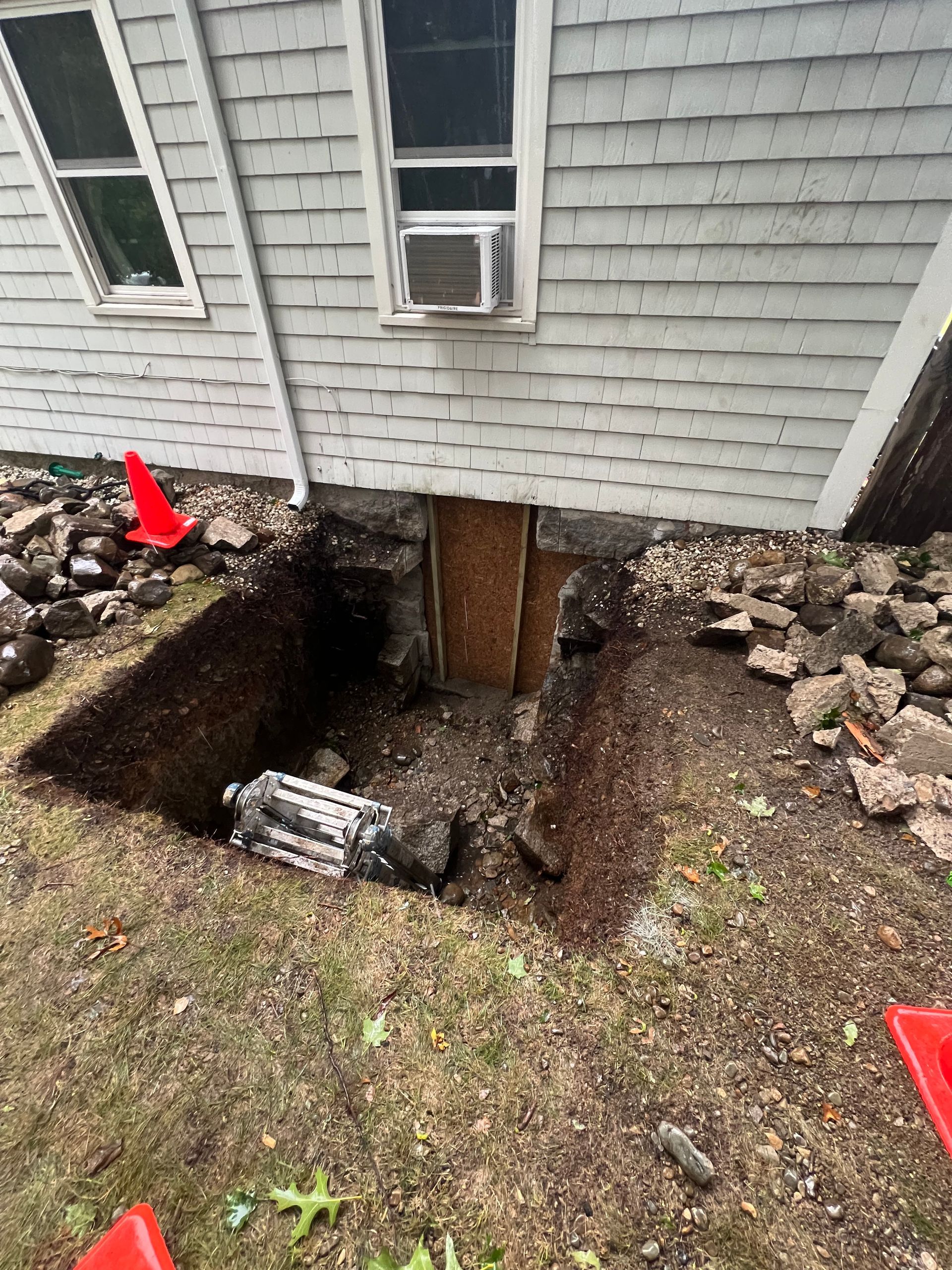 Exterior of house with dug out foundation, visible framing, dirt, and safety cones