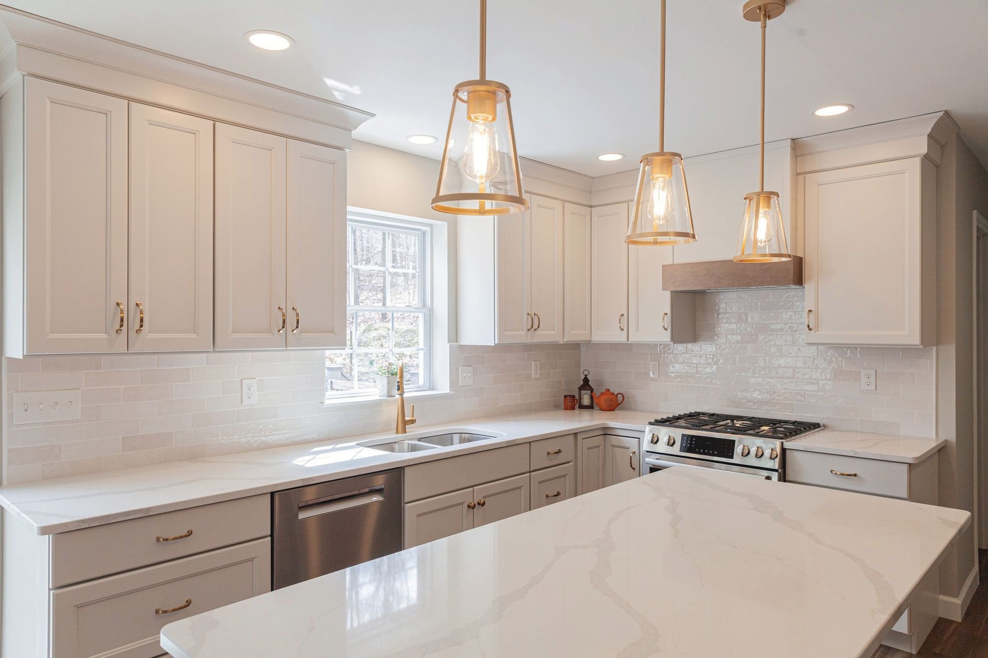 Bright modern kitchen with white cabinets, marble island, and pendant lights