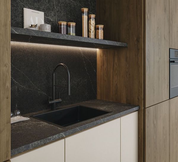 Modern kitchen nook with black sink, textured backsplash, under-cabinet lighting, and wood cabinetry