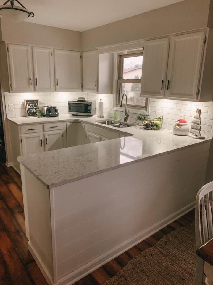 Bright white kitchen with island, cabinets, window, and countertops with small appliances and decor
