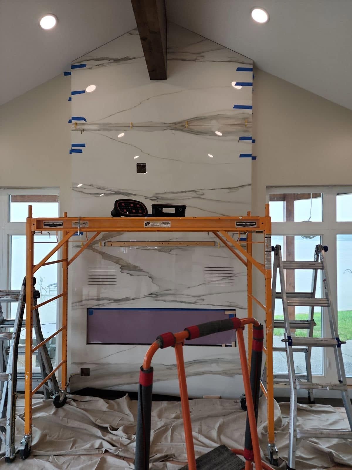 Scaffolding in a room with a large white wall panel being installed under a vaulted ceiling.