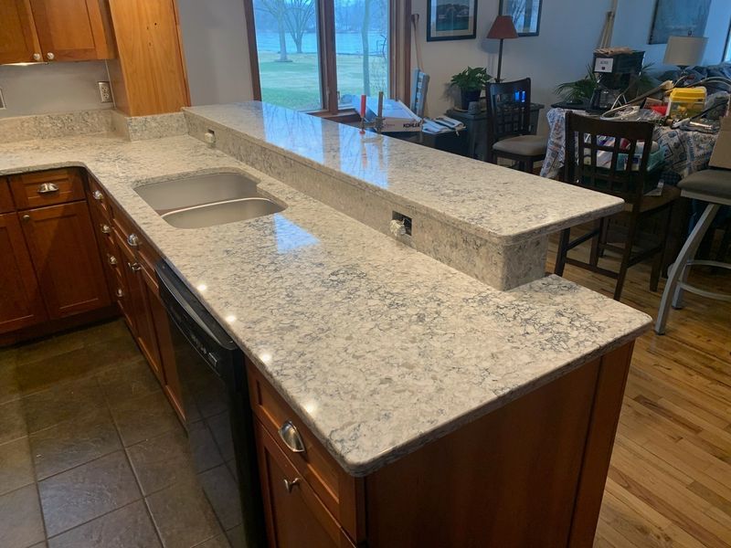 Kitchen island with granite countertop, built-in sink, and warm wood cabinets in a home interior