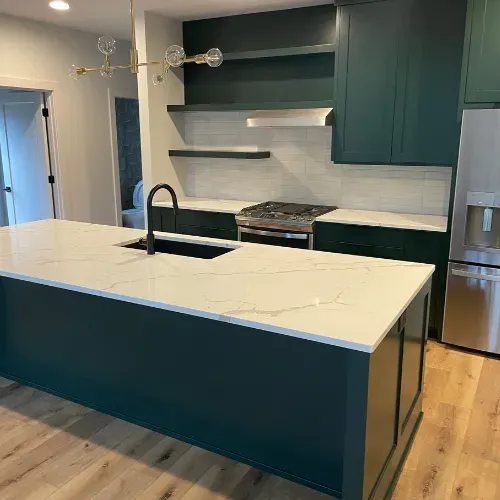 Modern kitchen with teal cabinets, white island, stainless appliances, and wood floors