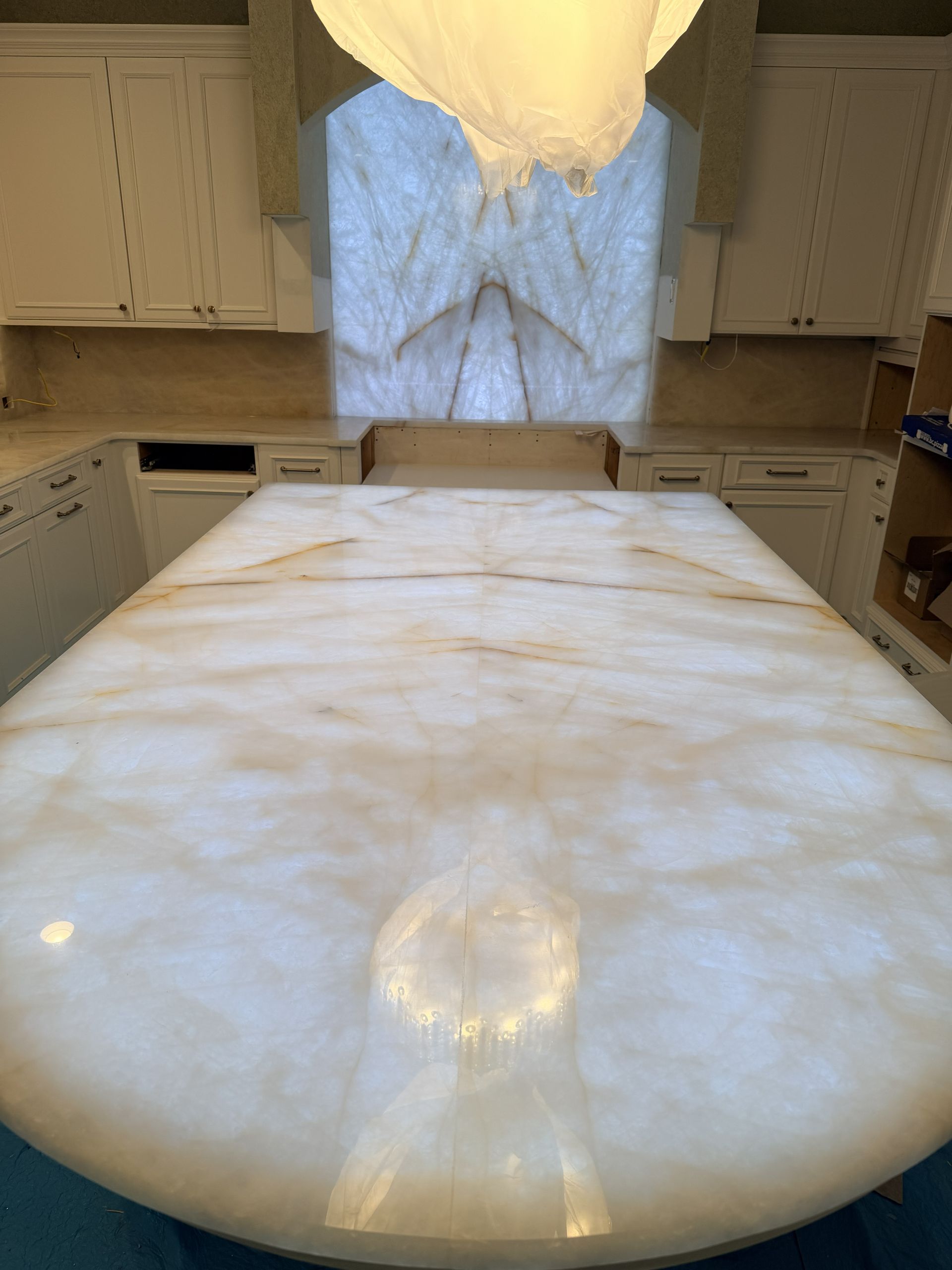 Bright marble kitchen island with white cabinets, a window, and a hanging pendant light.