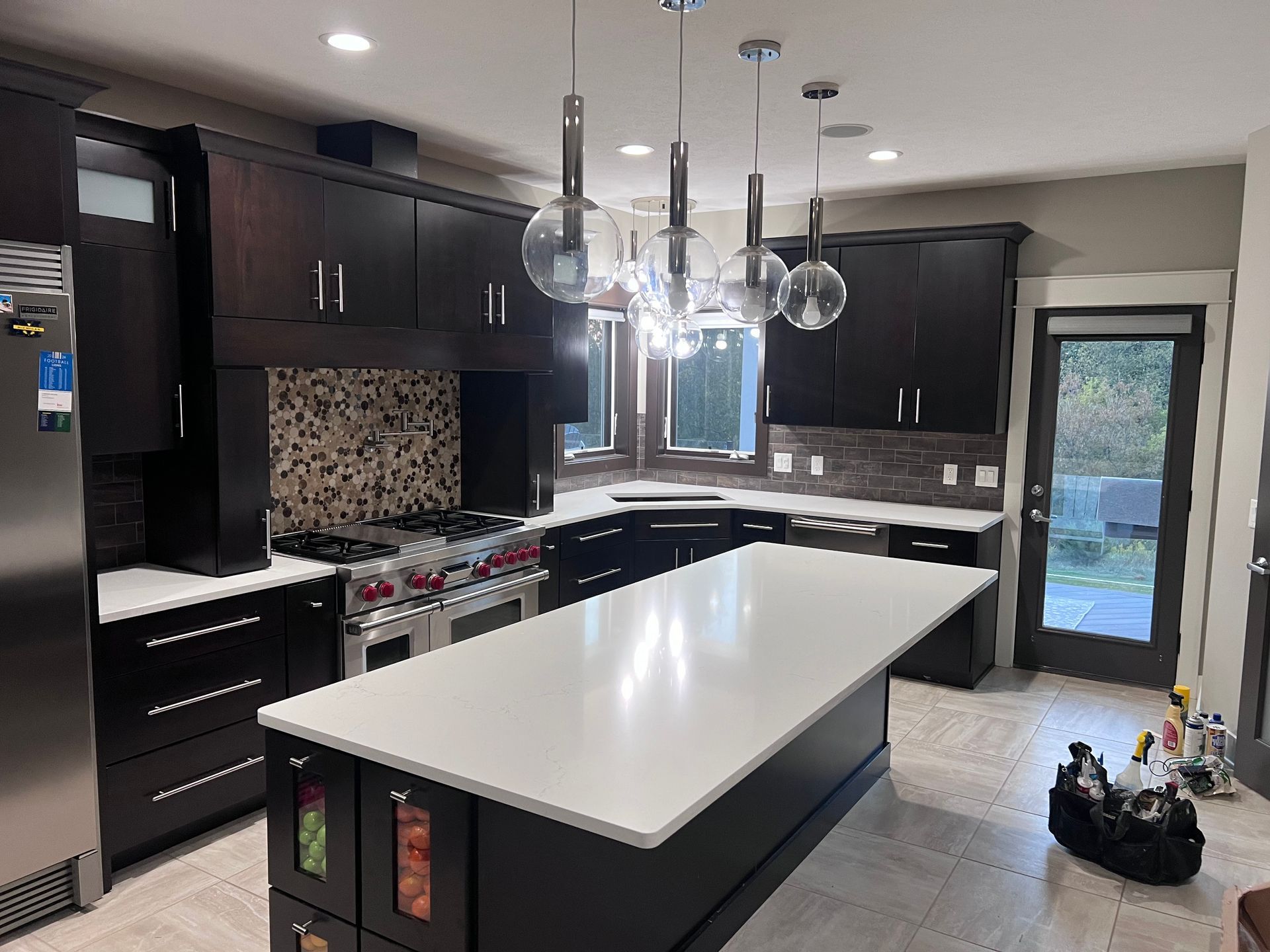 Modern vanity area with black countertop, pink tiled walls, and lit round mirror bulbs