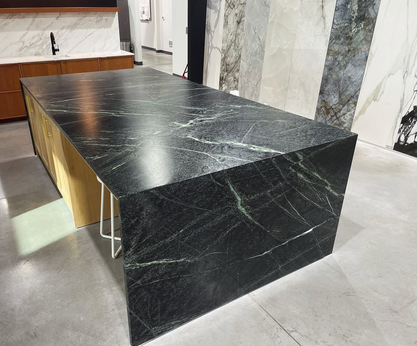 Black stone display table in a showroom with marble walls and floor.