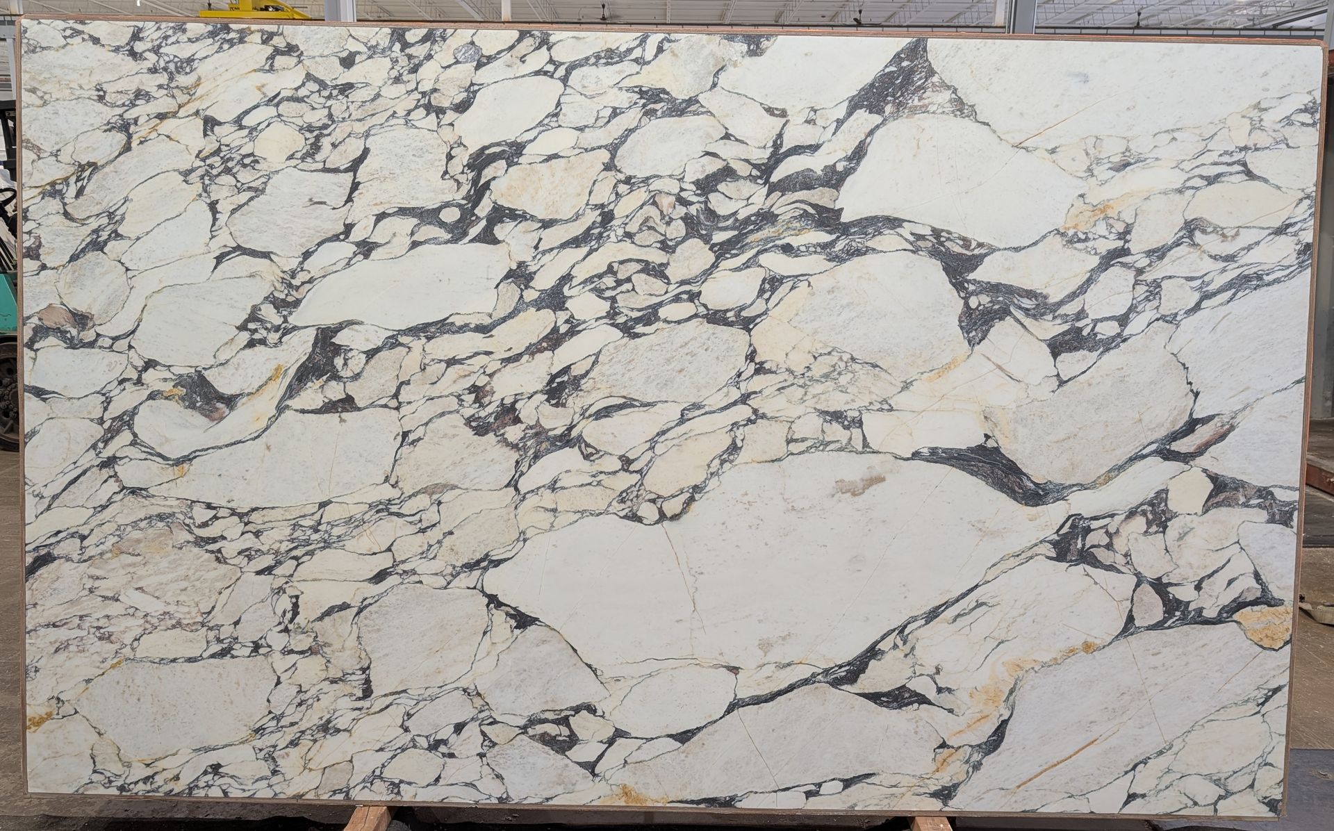 Marble-like stone slab with white and gray veining and cracks.