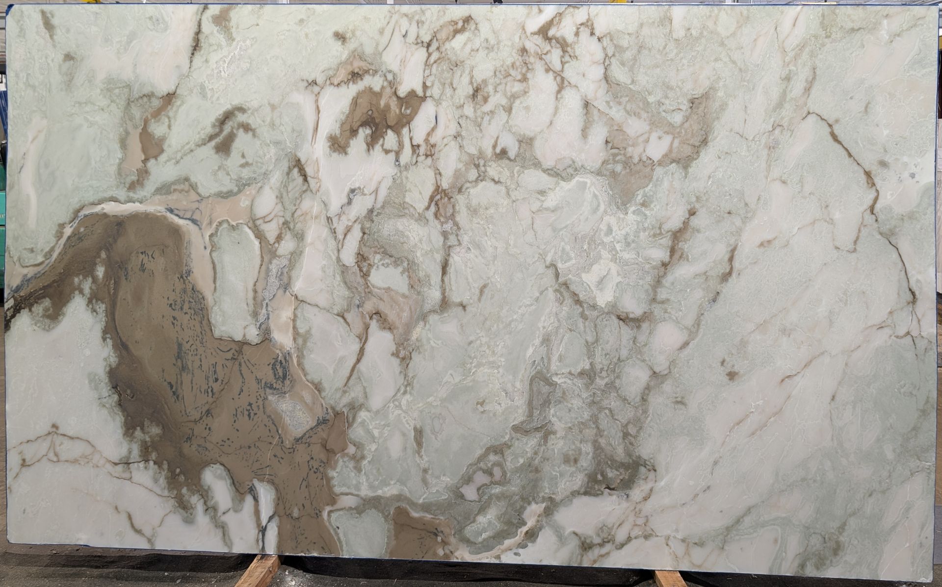 Veined white and beige marble slab with brown patches and a polished surface.