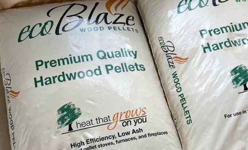 Various types of firewood, including logs, wood chunks, and pellets, are arranged on a wooden surface.
