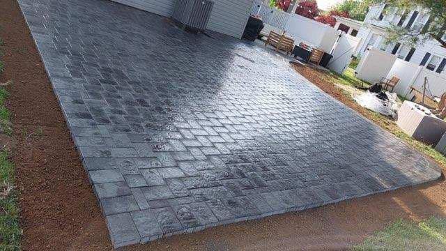 A brick driveway is being built in front of a house.