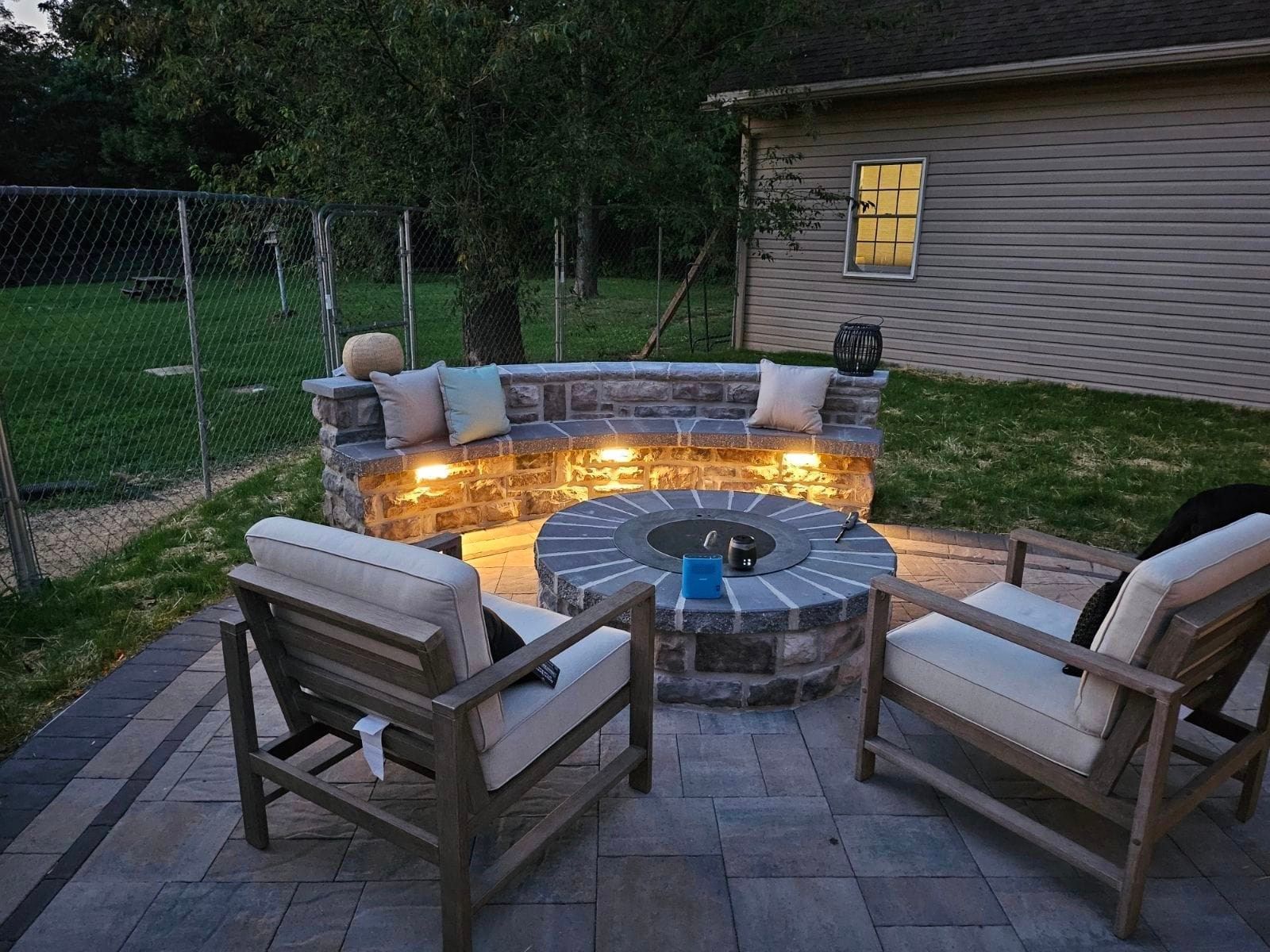 There is a fire pit in the middle of the patio with chairs around it.