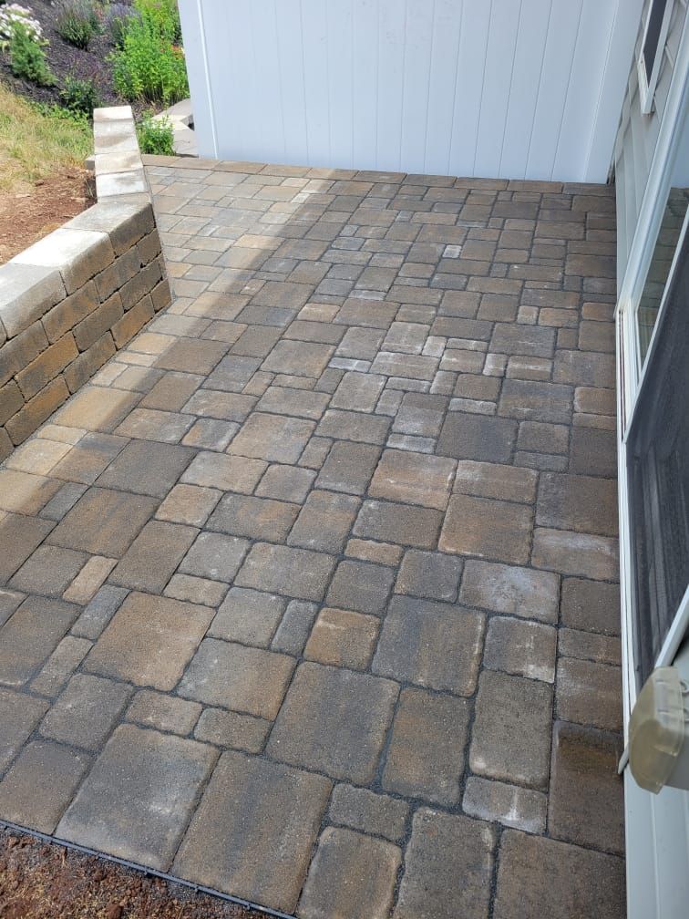 A brick patio is being built in front of a white house.