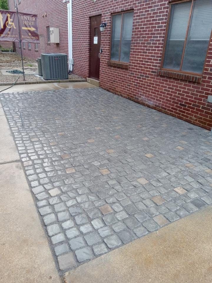 A brick building with a brick driveway in front of it.