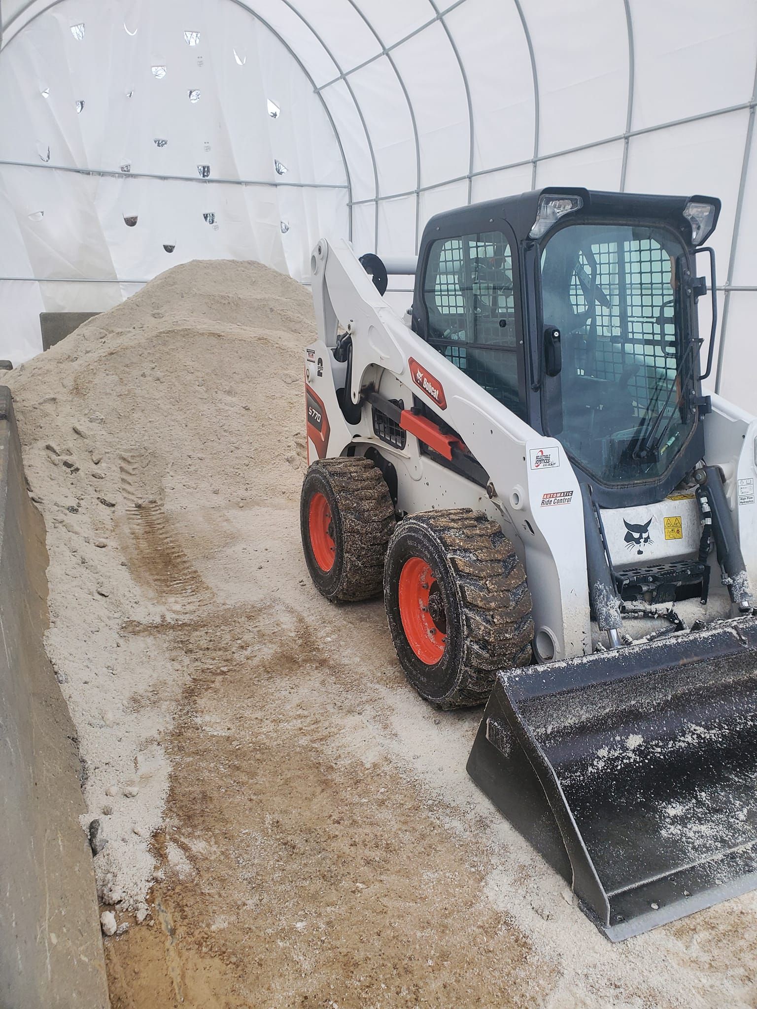 A bobcat skid steer is parked in front of a pile of dirt.