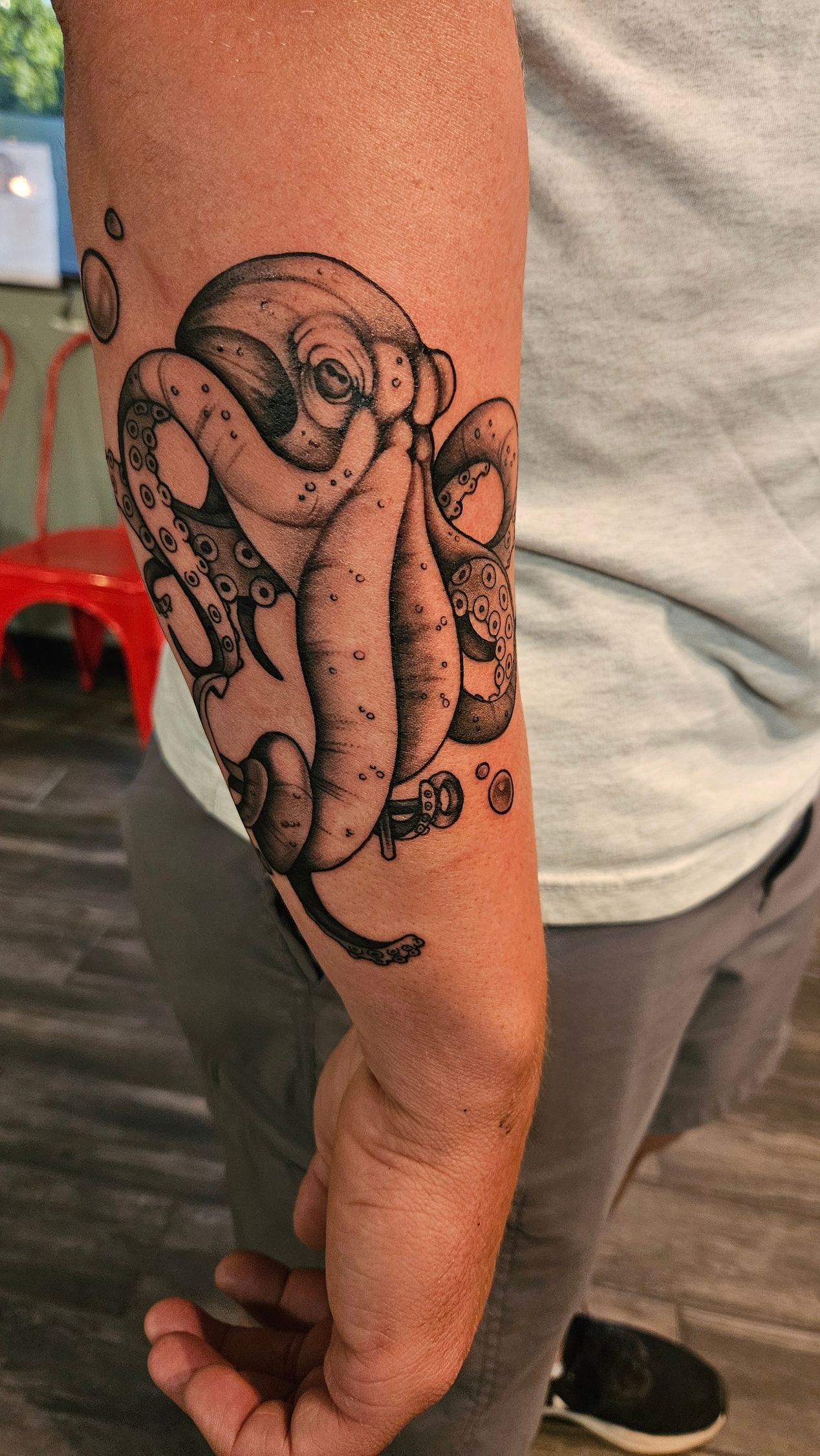 Close-up of an arm with a black snake tattoo on the forearm.