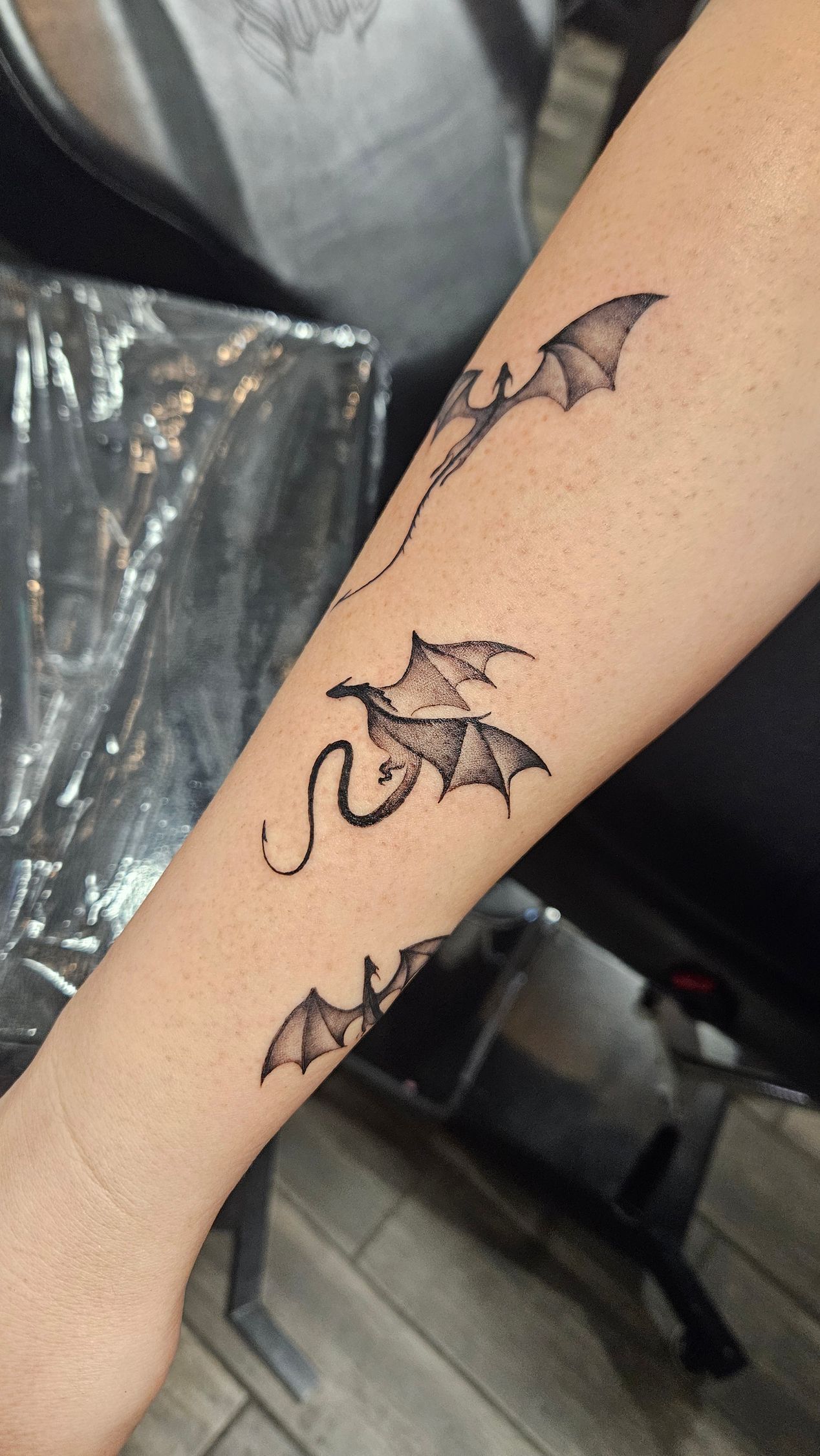 Forearm with three small black bat tattoos in a vertical line