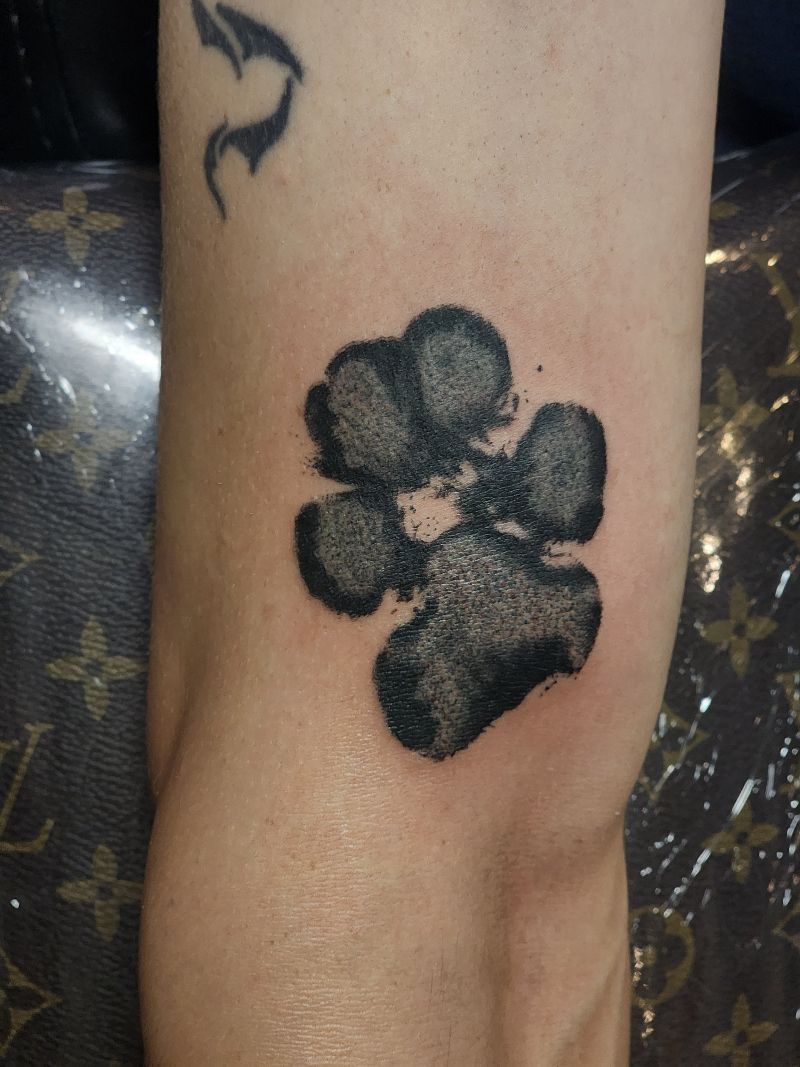 A person has a tattoo of a paw print on their arm.