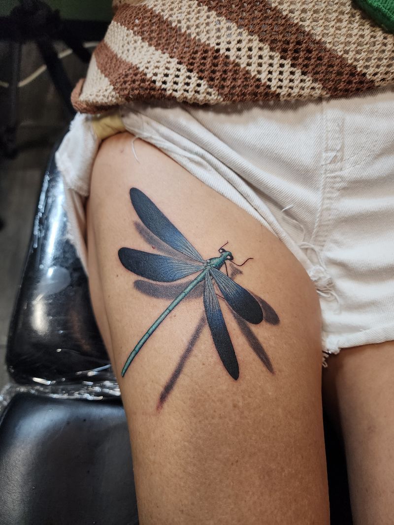 A woman has a dragonfly tattoo on her thigh