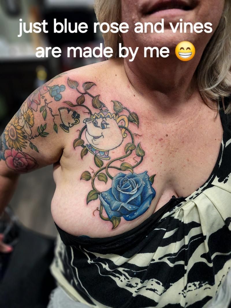 A woman has a tattoo of blue roses and vines on her chest