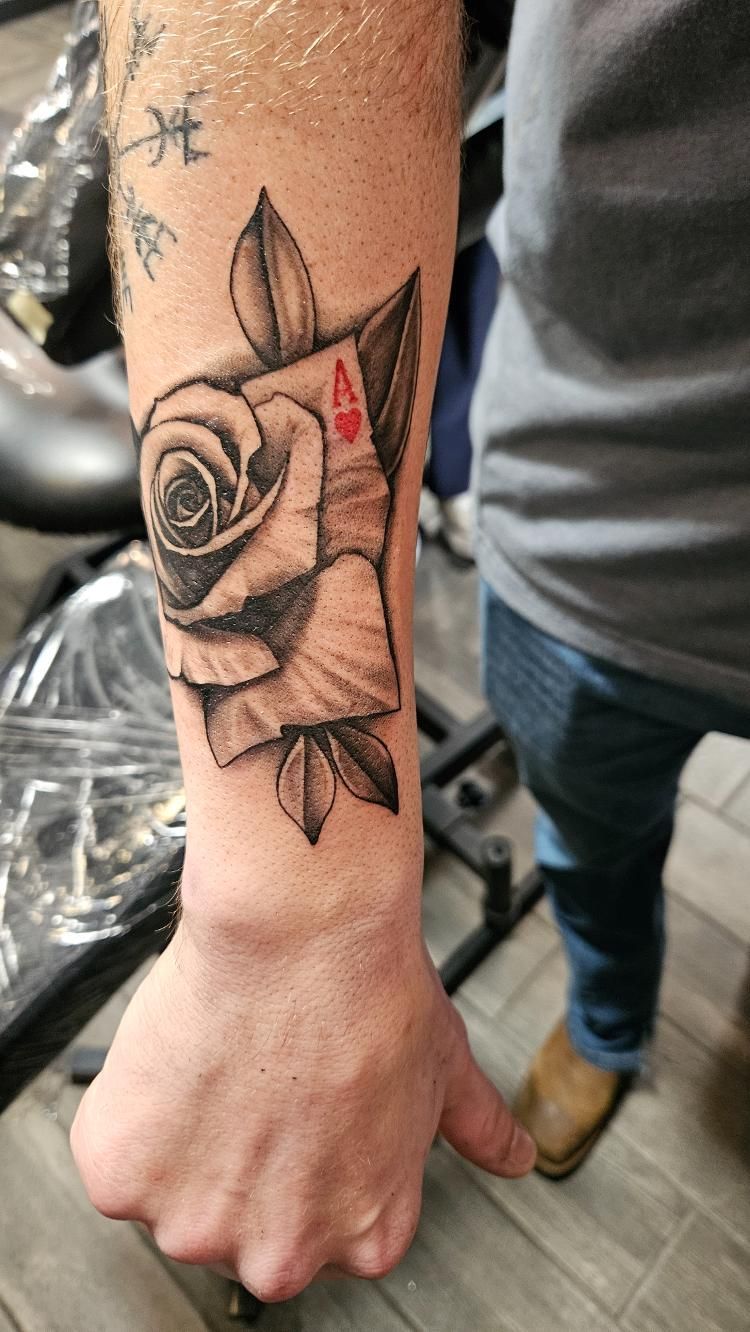 A man has a tattoo of a rose on his forearm.
