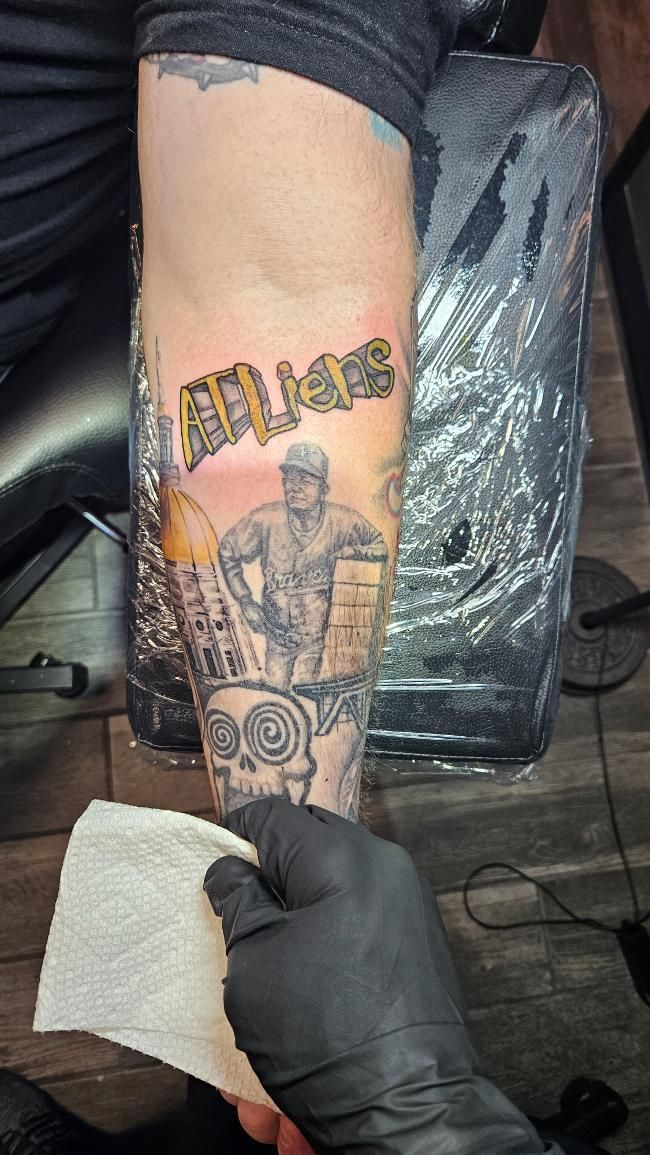 A person with a tattoo on their arm is holding a piece of paper.