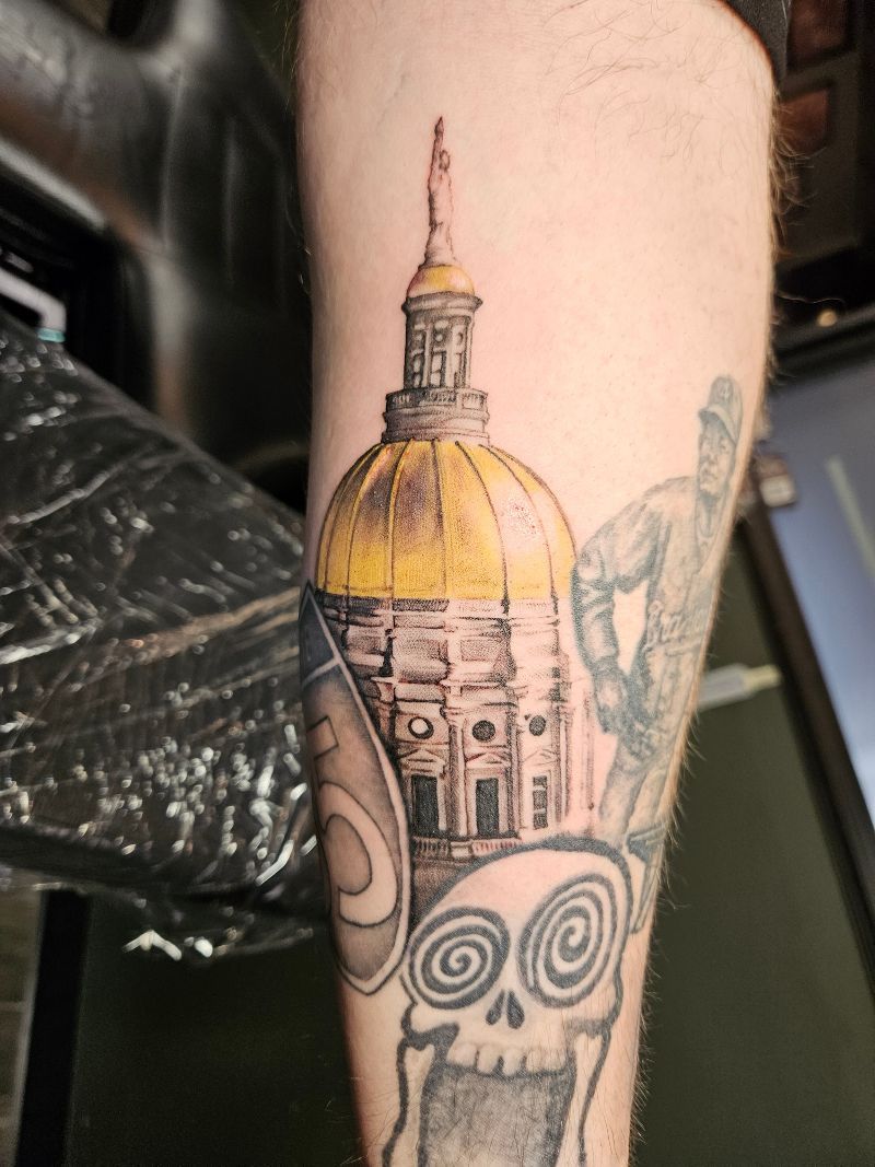 A person has a tattoo of a dome and a skull on their arm.